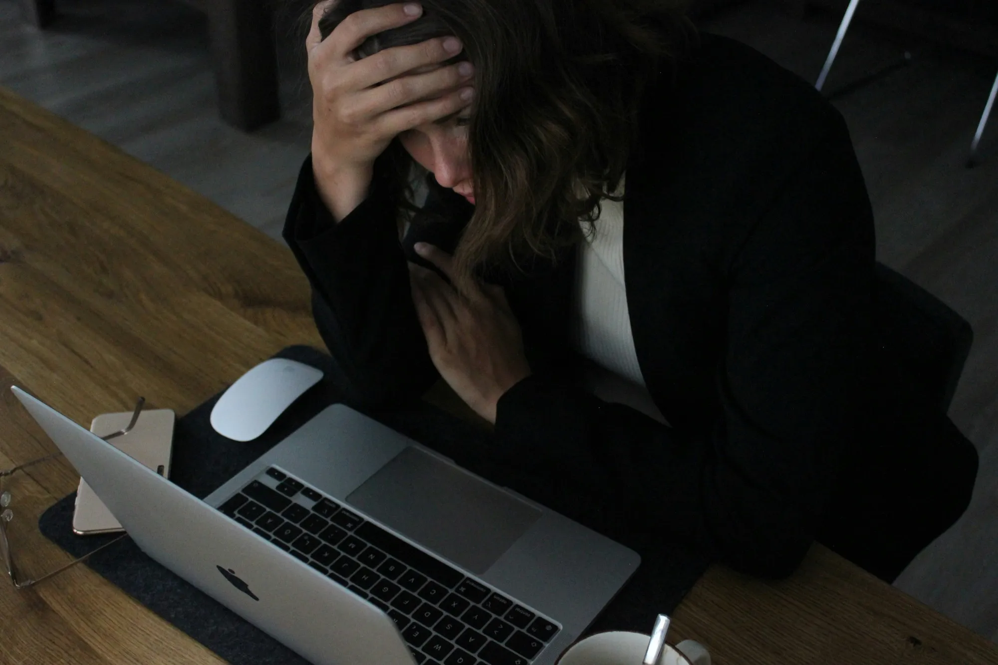 Une cheffe d’entreprise, la main dans les cheveux, regarde son ordinateur portable d’un air préoccupé.